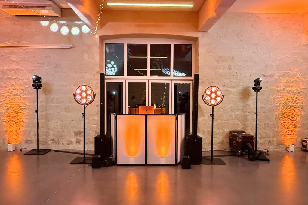 Régie DJ installée dans une salle en briques avec éclairage orange